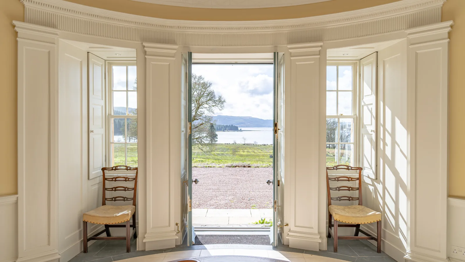 Asknish House, Lochgair: the bow room with its tall folding shutters drawn back and the garden doors open to Loch Fyne, the shutters, linings and panelled reveals repaired and refitted by our joiners