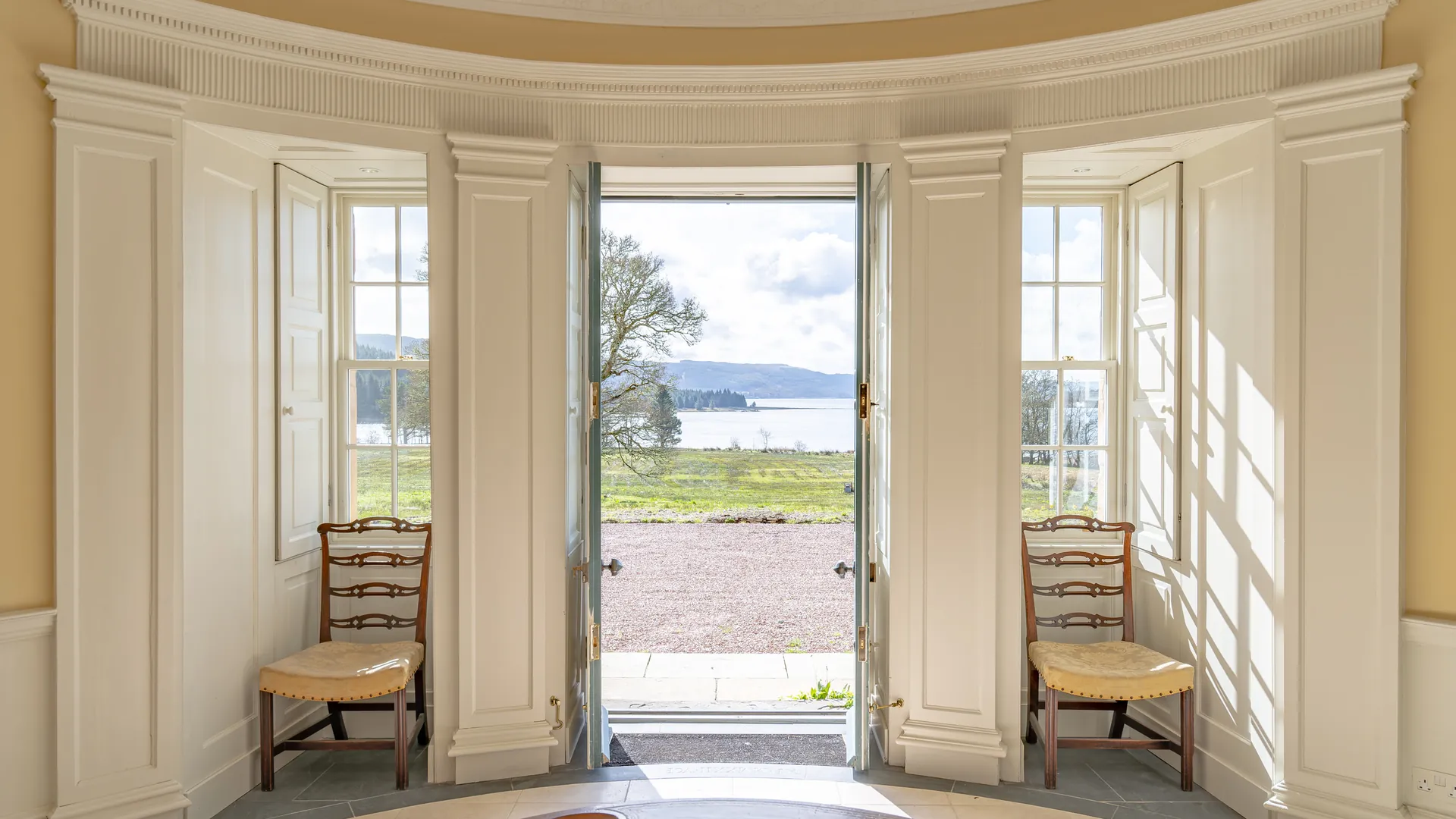 Asknish House on Loch Fyne: the bow room shutters folded back and the garden doors open to the loch, joinery repaired and refitted by LTM