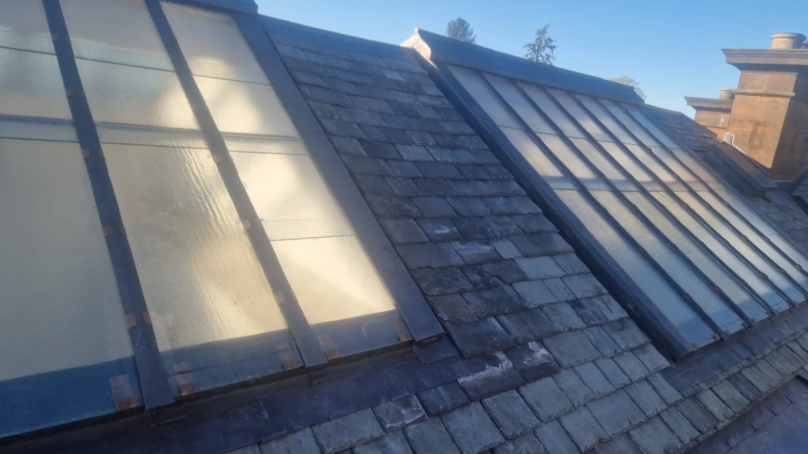 Runs of glazing set into a slate roof, every bar capped in lead and each pane held on copper tingles