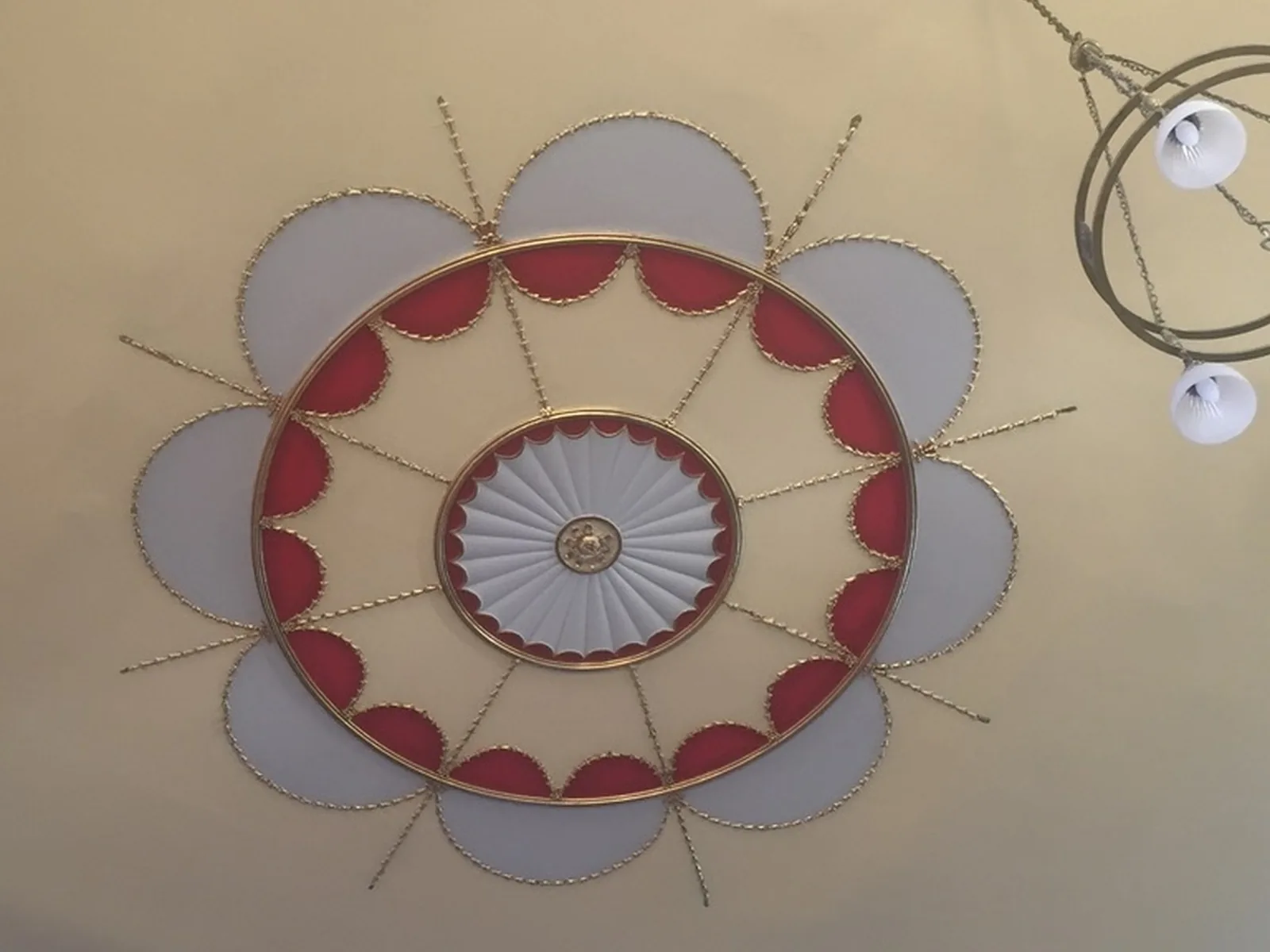 A painted Adam-style ceiling, its oval of husk chains and fan rose restored and redecorated in red and gold
