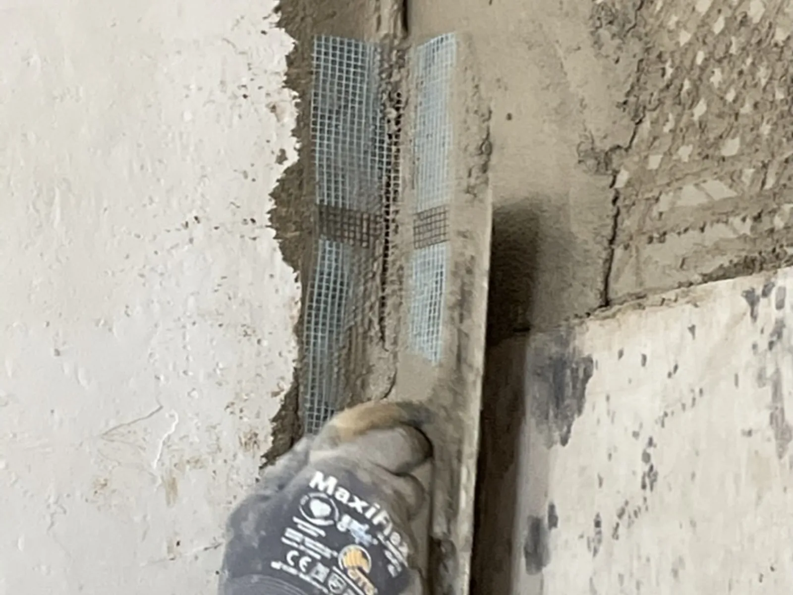 Floating lime plaster onto a window reveal with a wooden float, the arris formed against a rule