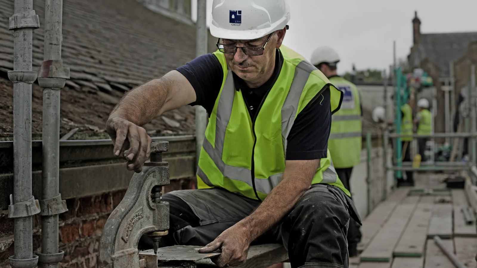 Dressing slate to size on the scaffold: every slate is holed, sorted and cut by hand