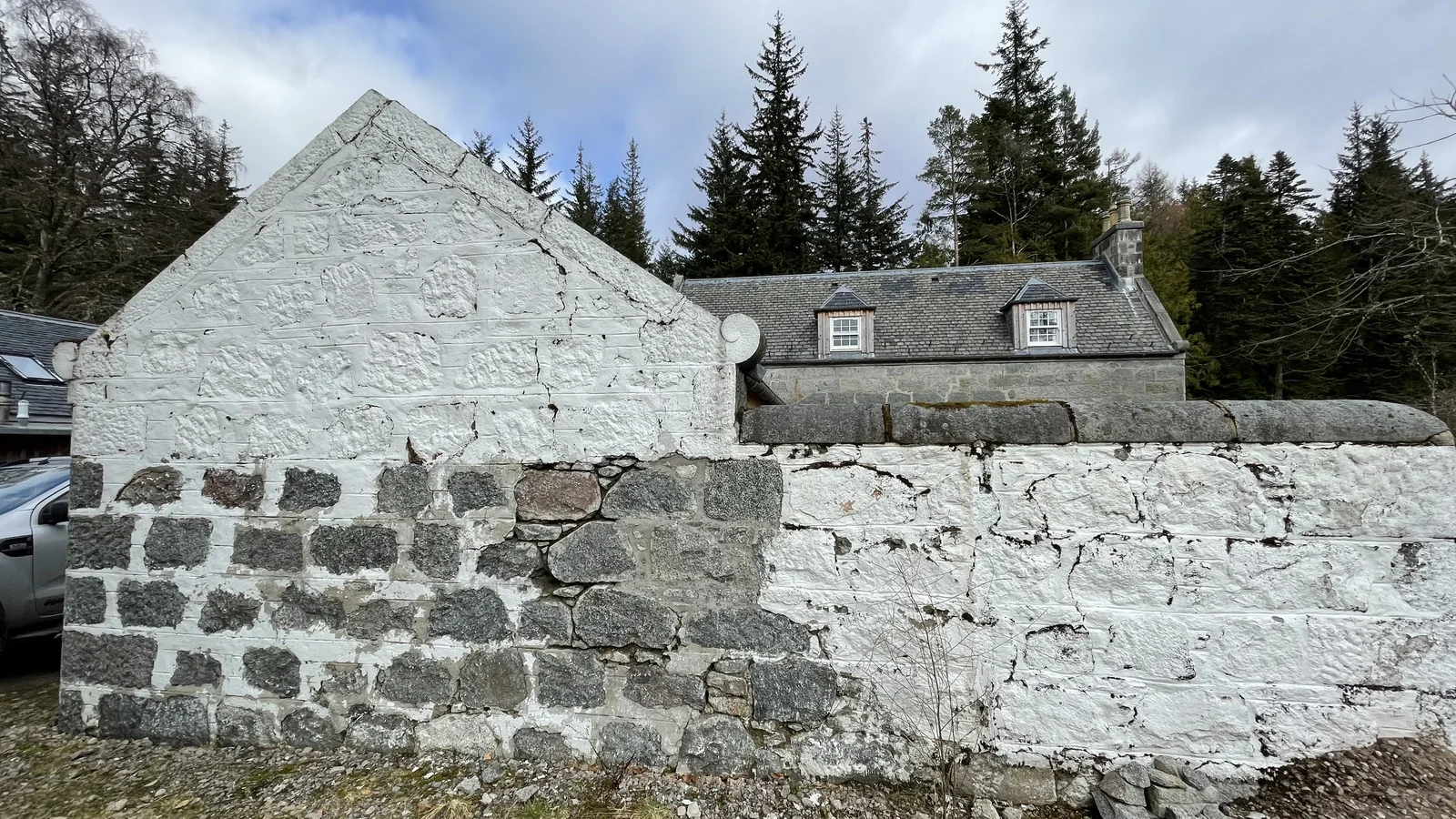 Corrour Estate: a granite gable half way through paint removal, the stripped stone on the left and the painted wall on the right
