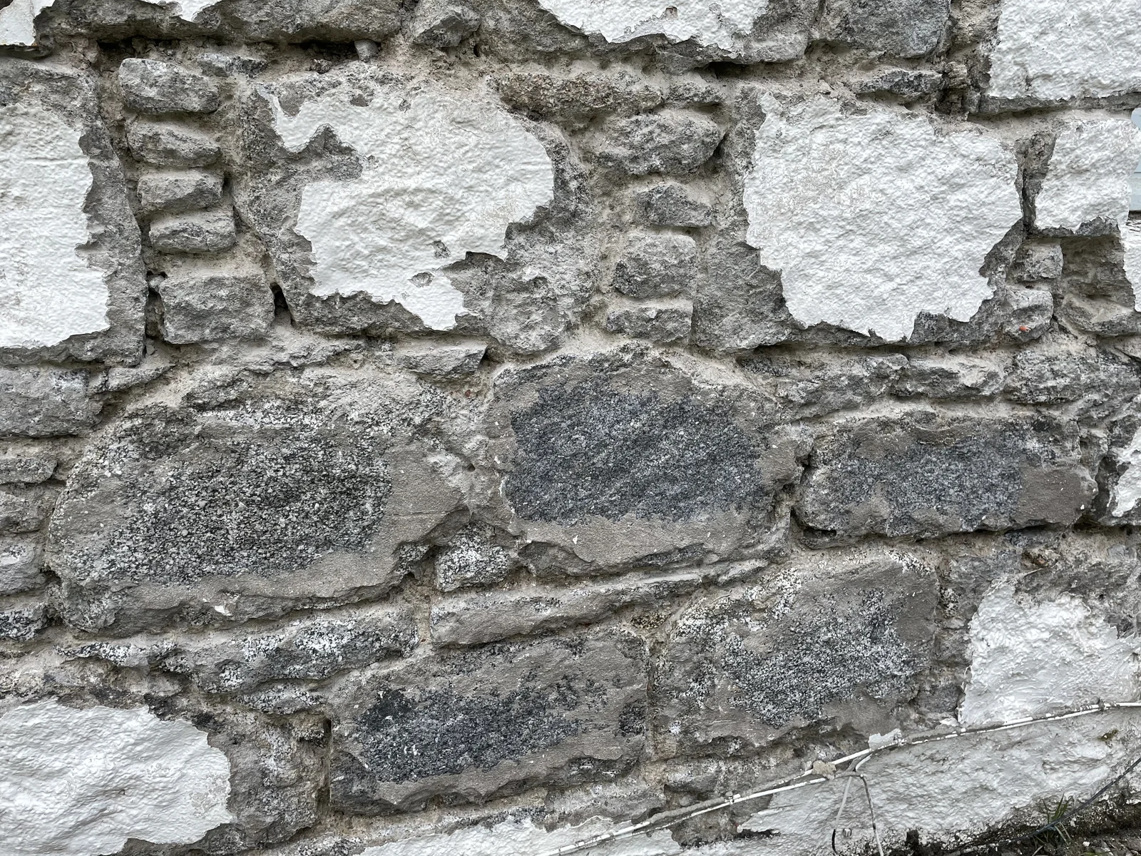 Masonry paint lifting from the granite: the coating had to come off before the cement pointing could be raked out and the walls repointed in lime
