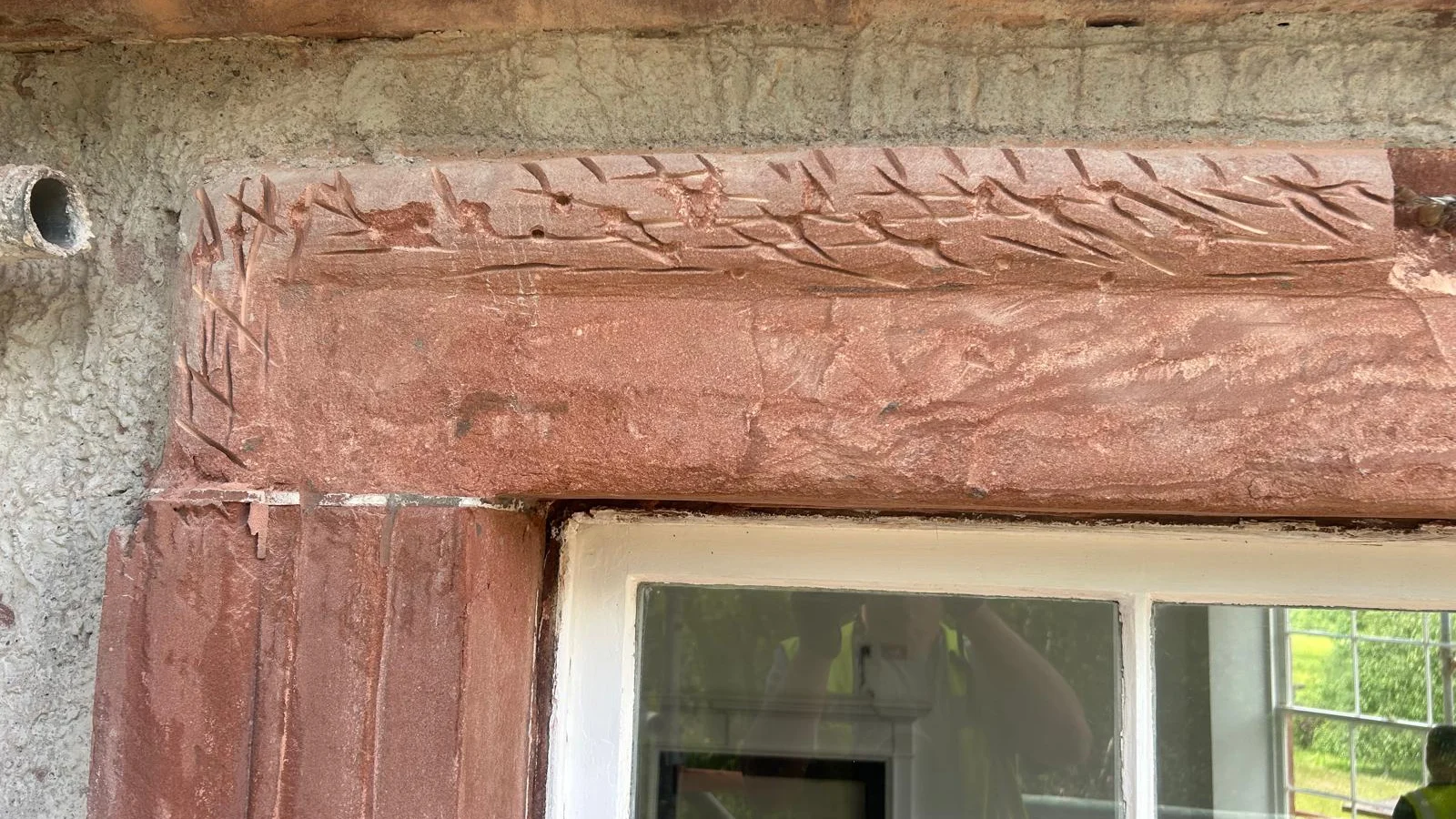A red sandstone window lintel and architrave cut back to sound stone and keyed with the chisel, ready for a lime mortar repair