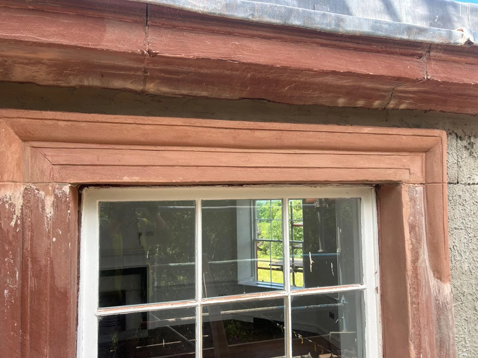 The finished repair: the architrave mouldings run true again across the lintel and down the jamb, toned to the red sandstone