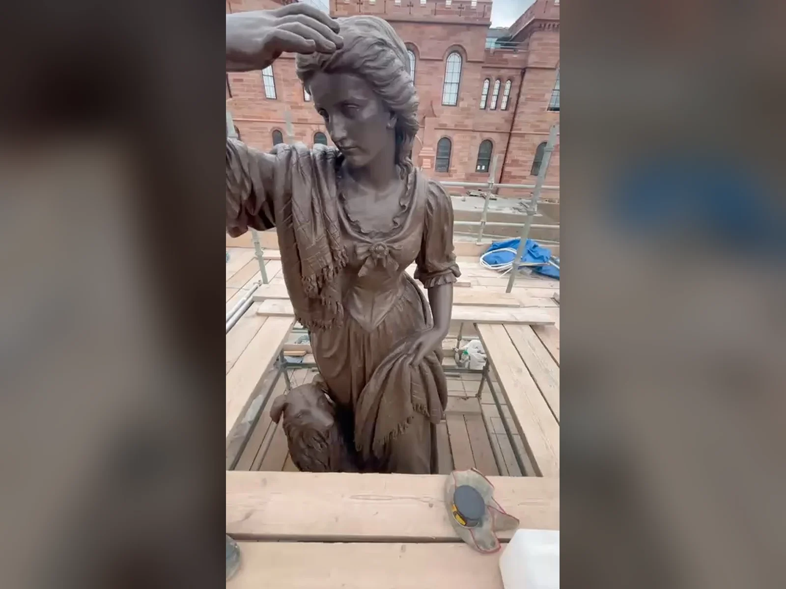 The bronze statue of Flora MacDonald at Inverness Castle, cleaned and re-waxed by our conservators from the scaffold, the castle behind