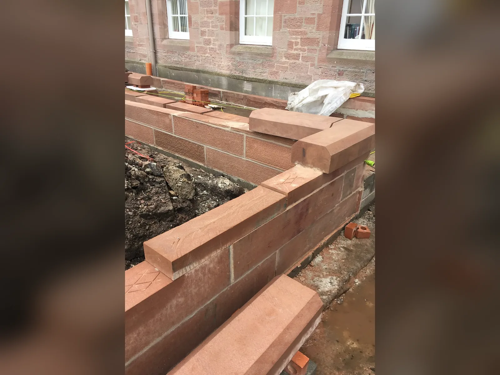 Inverness Castle: new red sandstone walling with dressed copes being built in lime mortar below the North Tower, each block cut and dressed to course with the castle behind