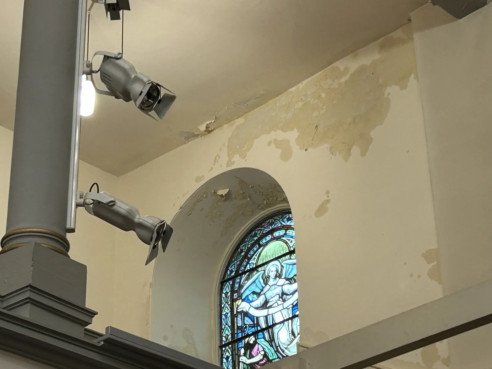 Inside the church: moisture staining and failed plaster on the hard above a window, the symptom the investigation set out to explain