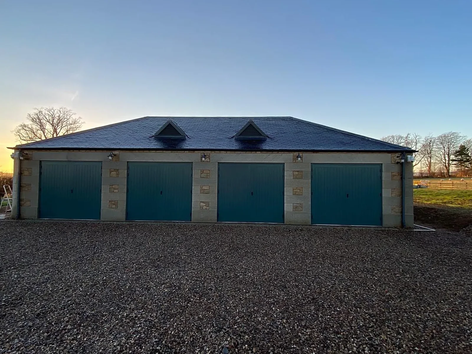 Cruiksfield House, Duns: a new four-bay garage in random rubble, squared Swinton dressings and Welsh slate, built by LTM from the groundworks to the doors beside a Category B listed house