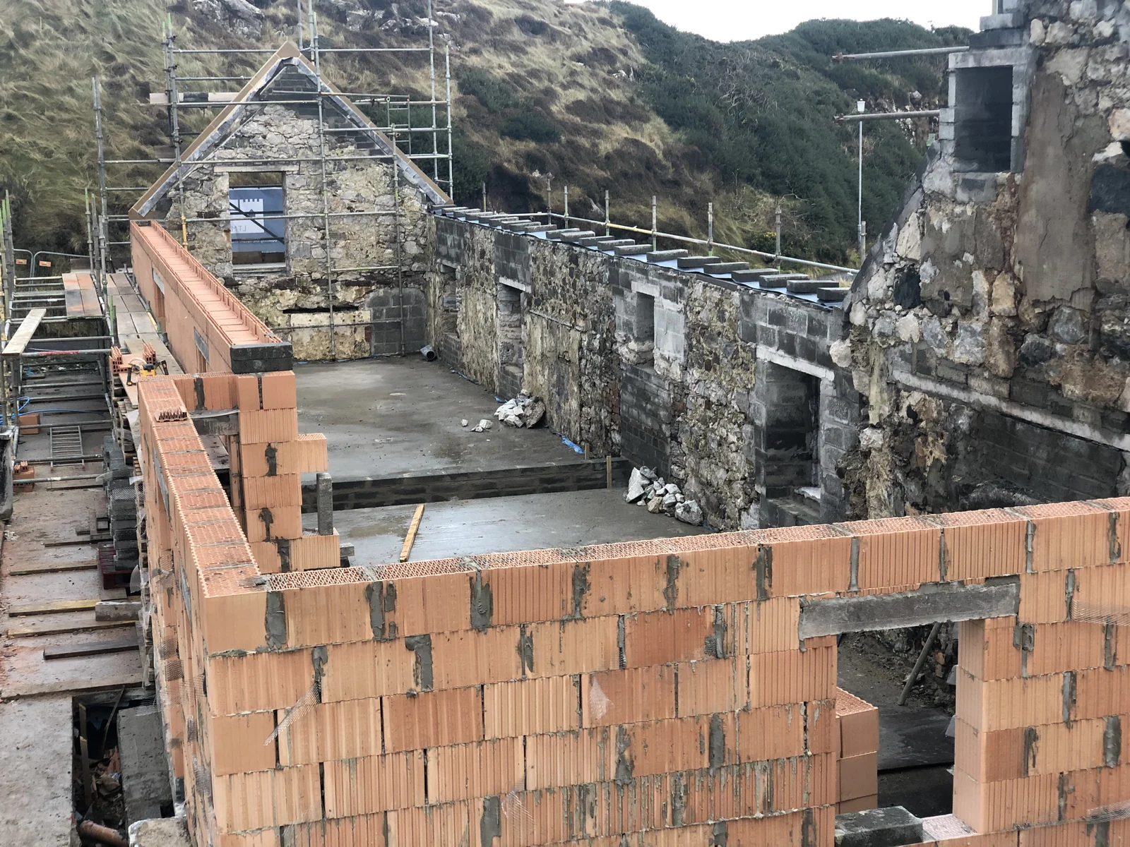 Rodel House, Isle of Harris: the East Range rising in Thermoplan fired-clay block against the restored rubble walls of the 18th-century house