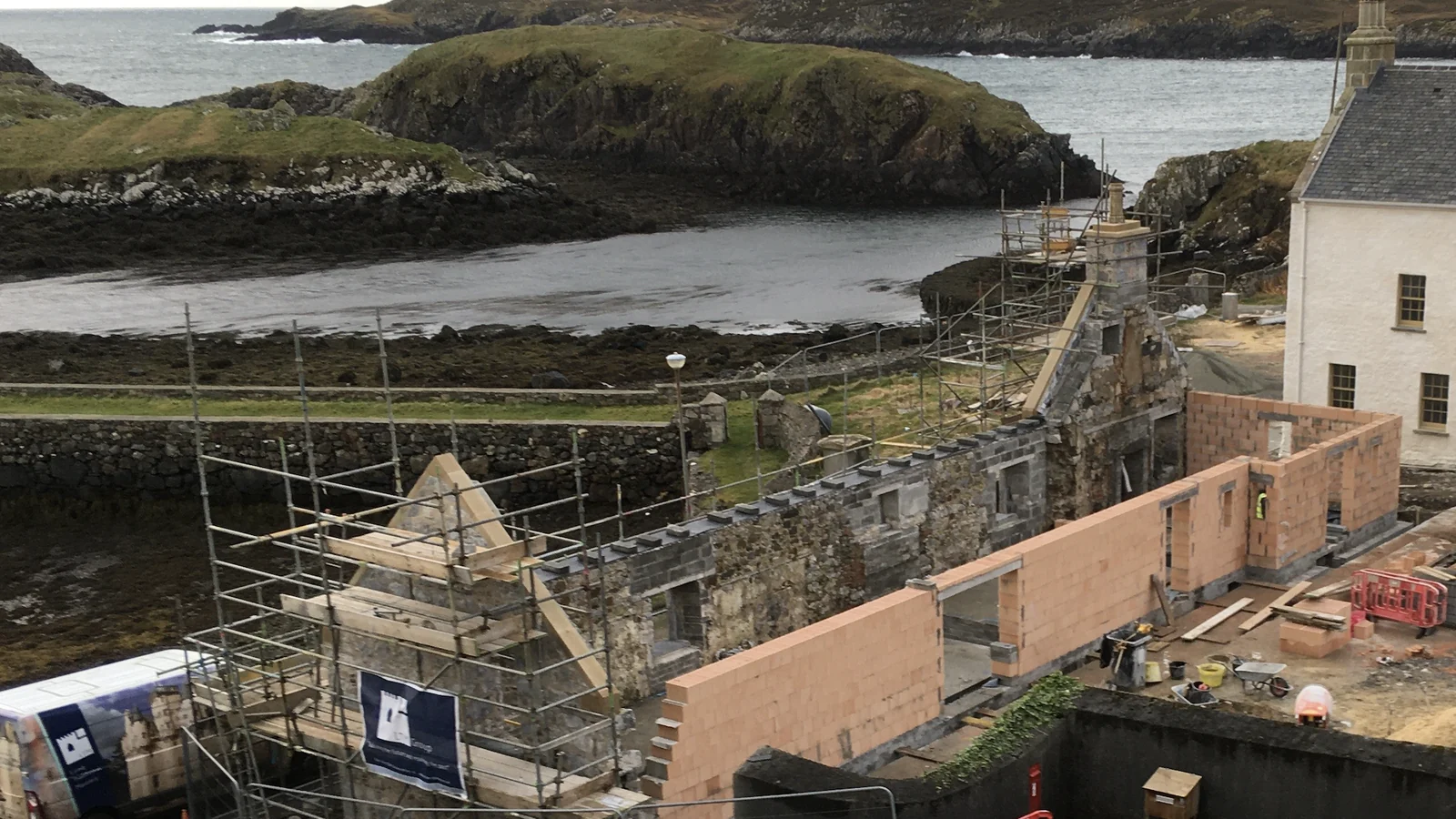 Rodel House from the shore: the new East Range and Sail Loft under construction in clay block beside the house, on an exposed Atlantic site reached by ferry